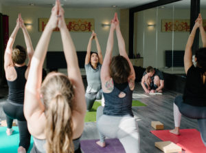Women practising Yoga Warrior 1 posture in Barefoot Birmingham Studio