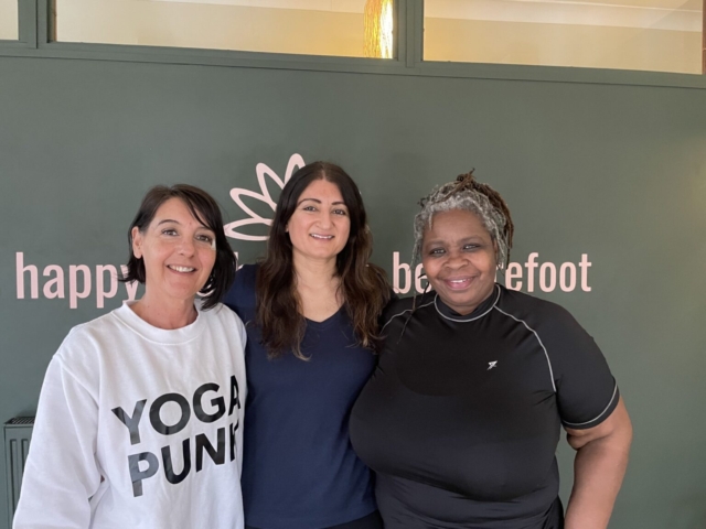 Three family carers in the Barefoot Birmingham Yoga Studio, smiling after their class.