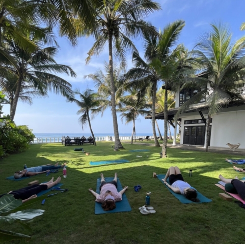 Women on the grass in savasana pose at a Sri Lanka Yoga retreat